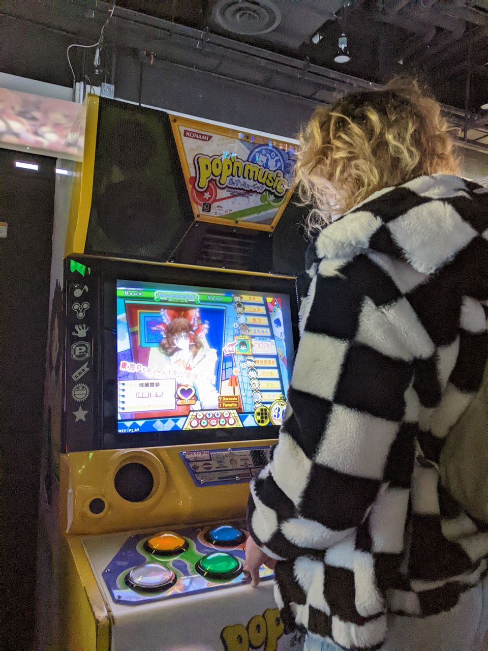 daphnis playing a pop'n music arcade machine wearing a ska print sweater
